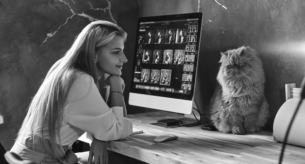 Beautiful young woman is sitting next to the table while her cat is sitting on the table.